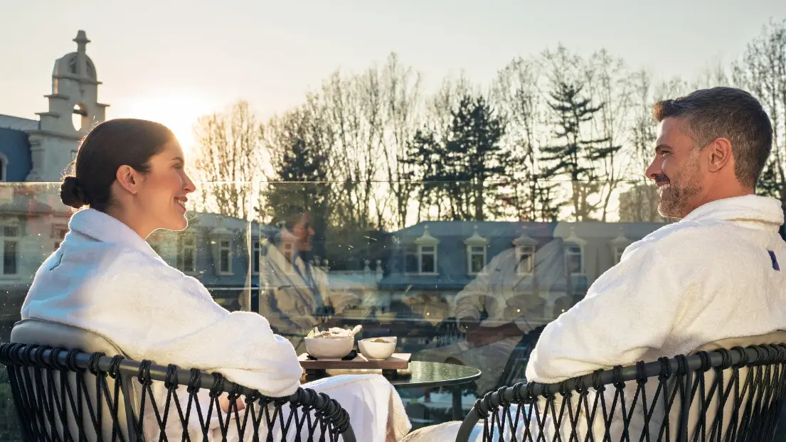 A couple in bathrobes have breakfast on the balcony overlooking the castle.