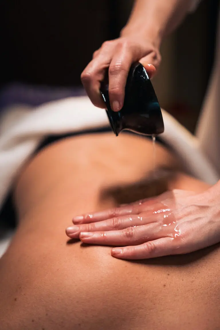 Hands massaging a person's back with oil in a spa
