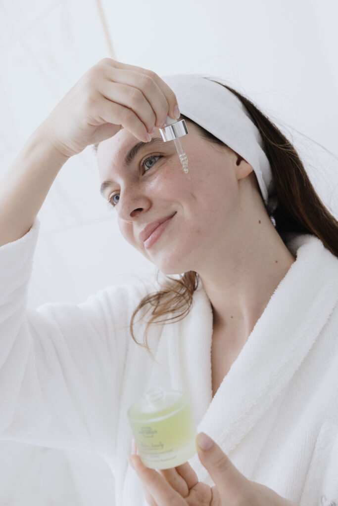 Donna in accappatoio che applica il siero per il viso, godendosi il relax quotidiano.