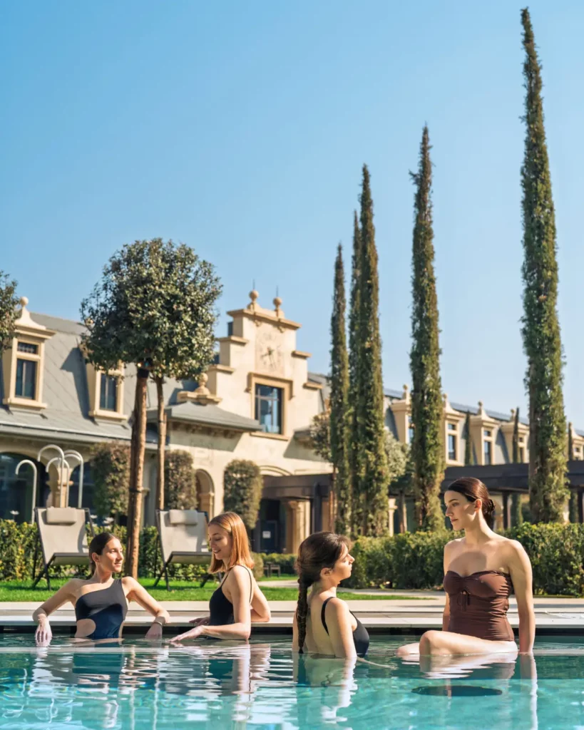 Four women relaxing by the pool with a villa in the background